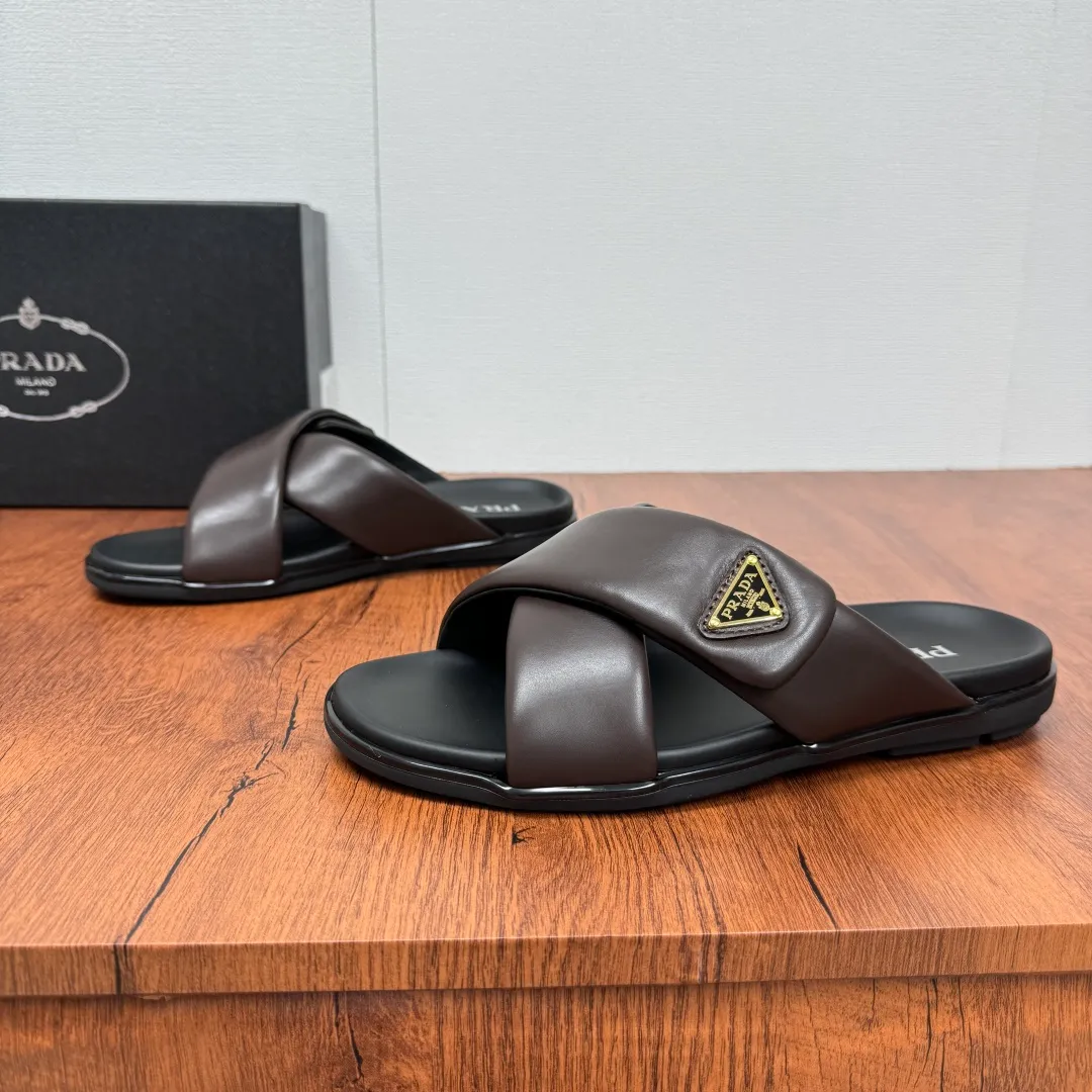 Batch 580 Prada/Prada's new men's leather cross slippers. Velcro closure can finely adjust the size. Calf leather light luxury slippers. Thick soft calf leather wraps the upper. Fat but soft rubber lazy style, soft and comfortable, excellent foot feel. Genuine leather bottom layer, cross style, with a Velcro closure buckle, easy to adjust the appropriate size, and a perfect fit for the wearing experience. The enamel gold triangle logo highlights the brand's classic features. Lightweight rubber thin sole, high foot comfort! Complete package! Size: 39-40-41-42-43-44-45 Leather shoe size Item number: 2X7132 Brown